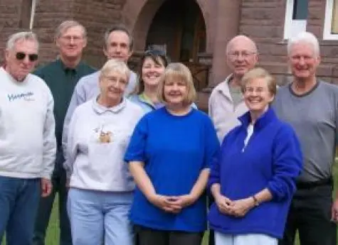 A group of church members standing together outside the brick church building