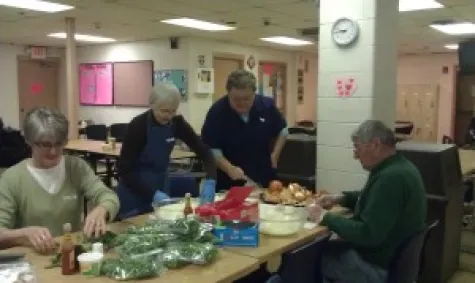 Volunteers preparing greens and food together in the church kitchen