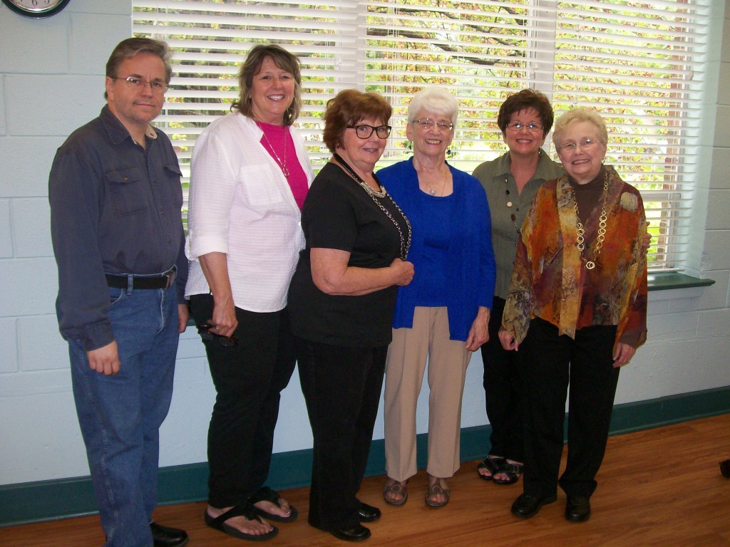 Six community members standing together by a window
